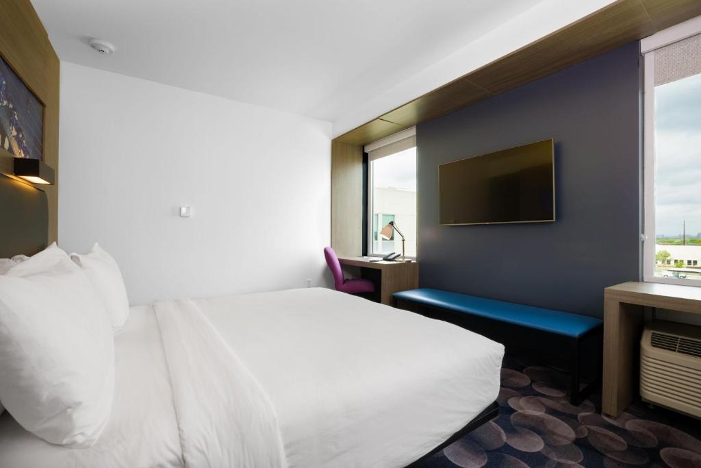 a hotel room with a white bed and a window at Aloft Austin Airport in Austin
