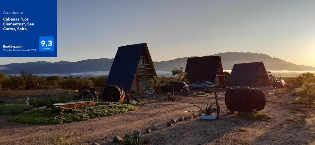 a group of huts in the desert with the sun setting at Cabañas "Los Elementos", San Carlos, Salta, in San Carlos