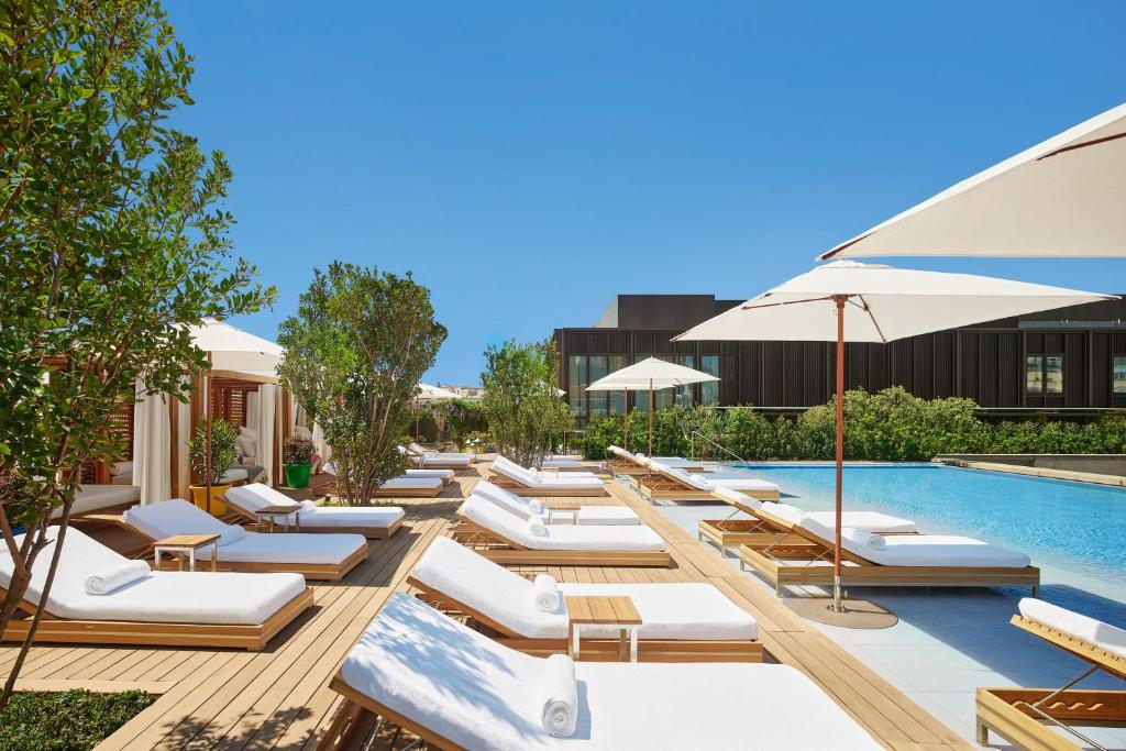 a row of lounge chairs next to a swimming pool at The Madrid EDITION in Madrid