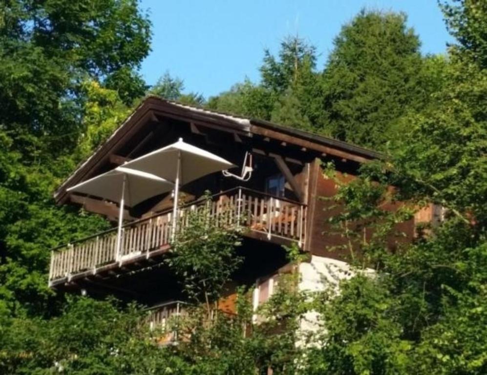 a house with a deck with an umbrella at Chalet Hüsli in Giswil