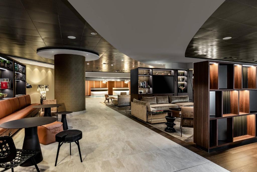 a lobby with couches and tables and a television at Frankfurt Airport Marriott Hotel in Frankfurt/Main