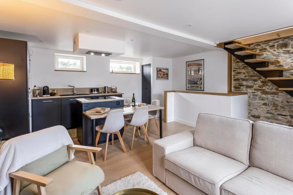 een woonkamer met een bank en een tafel met stoelen bij Le 37 - Maison 2 chambres en bord de mer in Saint-Cast-le-Guildo