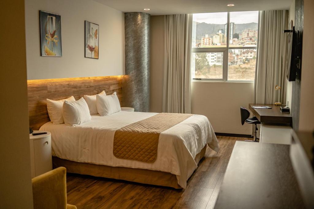 Cette chambre comprend un lit, un bureau et une fenêtre. dans l'établissement Hotel La Peonía, à La Paz