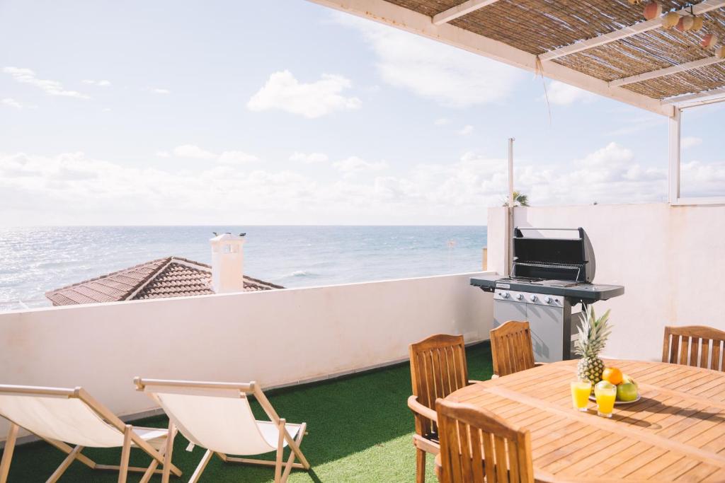 uma varanda com uma mesa e cadeiras e o oceano em Duplex Victoria Beach Málaga em Cala del Moral