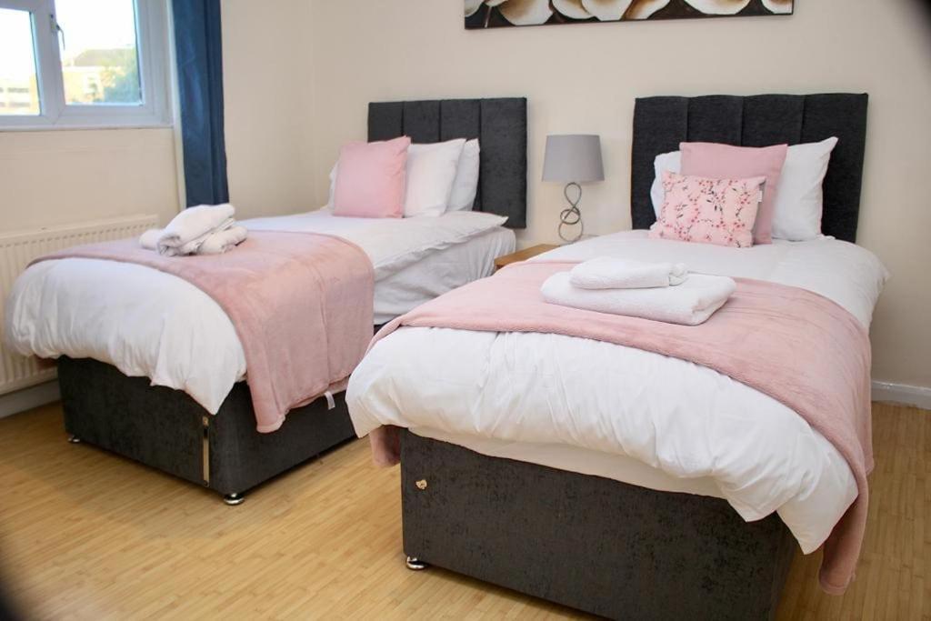 a bedroom with two beds with pink and white sheets at Contractor's Haven- 4-Bedroom House with Free Parking, Super Fast WiFi, Fran Properties in Aylesbury, Pets are Welcome in Buckinghamshire