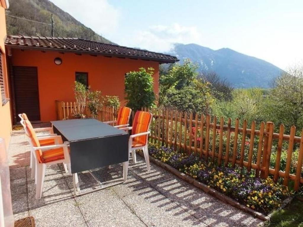 un patio trasero con una mesa y sillas y una valla en Al Colombajo, en Intragna
