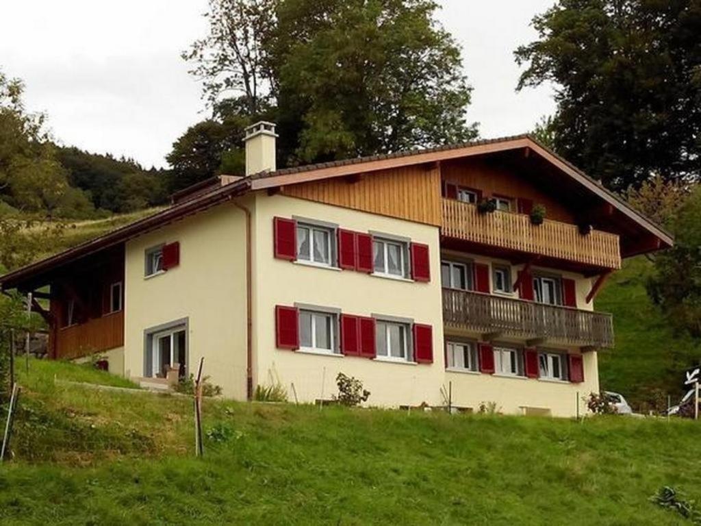 a large house with red shutters on a hill at Ferienwohnung im Bauernhaus in Chardonne