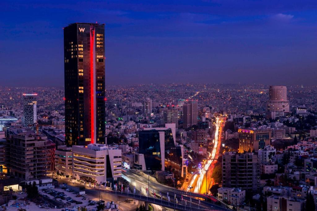a city skyline at night with a tall building at W Amman Hotel in Amman