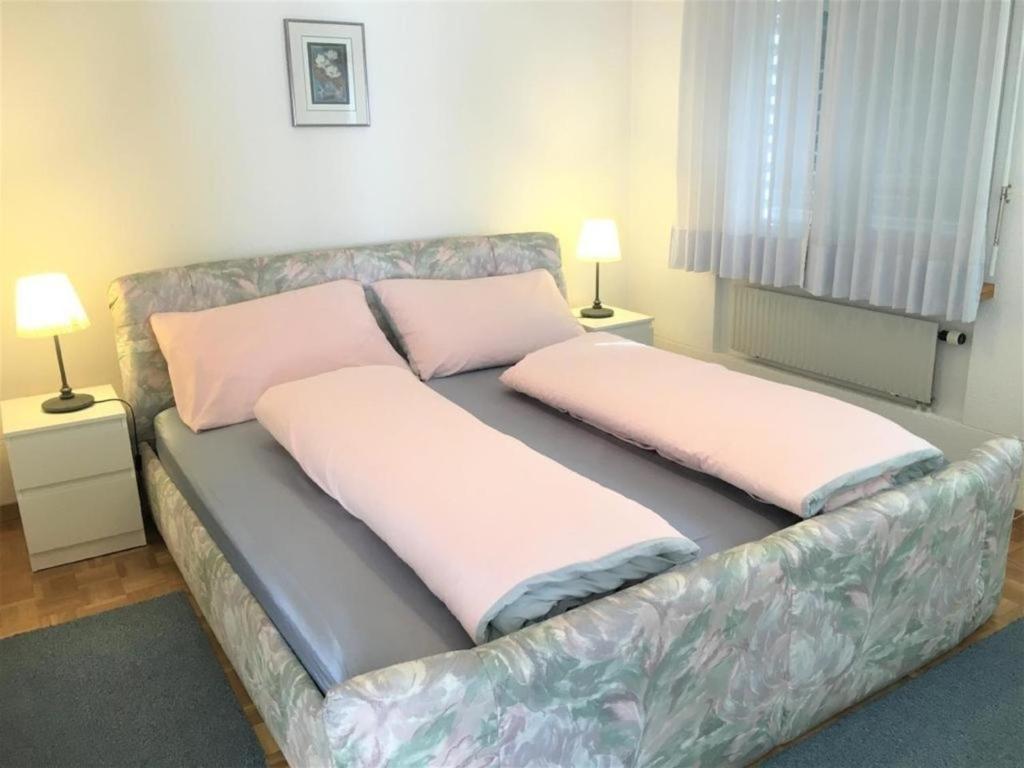 1 cama con 2 almohadas en una habitación en Schöne, sonnige 25-Zimmer Parterre-Ferienwohnung, en Poschiavo