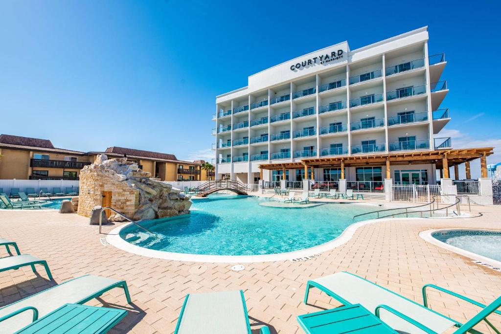 サウス・パドレ・アイランドにあるCourtyard South Padre Islandのホテルの正面にプールと椅子があります。