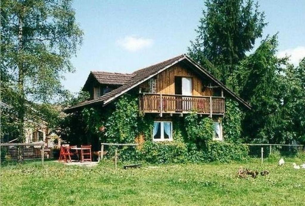 a wooden house with a balcony in a field at Alten-Hof in Bischofszell