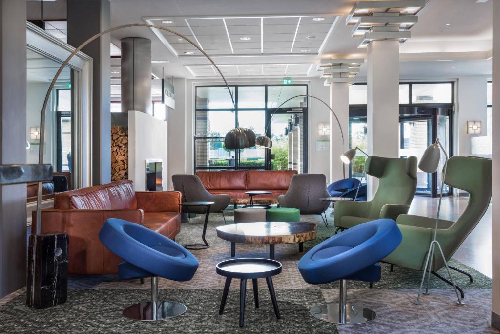hol z kanapami, krzesłami i stołami w obiekcie Courtyard by Marriott Amsterdam Airport w mieście Hoofddorp