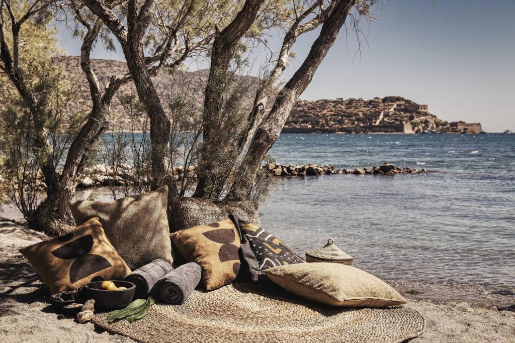 a blanket and pillows on a beach near the water at Domes of Elounda, Autograph Collection in Elounda