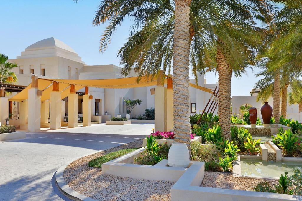 a courtyard with palm trees and a building at Al Wathba, a Luxury Collection Desert Resort & Spa, Abu Dhabi in Abu Dhabi