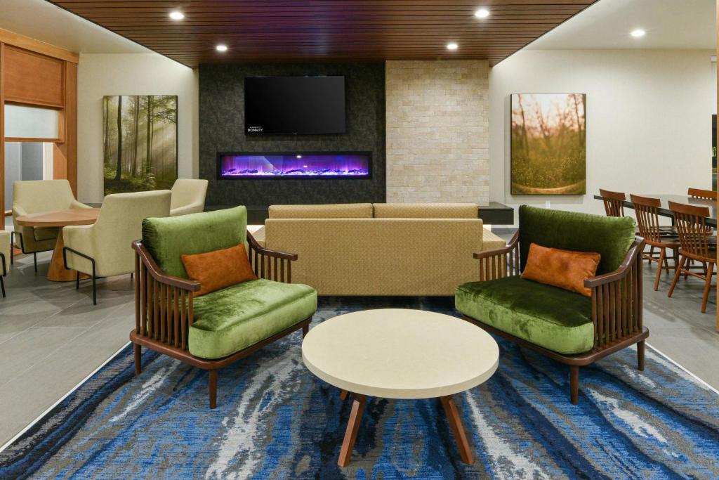 Fairfield Inn & Suites by Marriott Moorpark Ventura County في Moorpark: غرفة انتظار مع كراسي وطاولات وتلفزيون