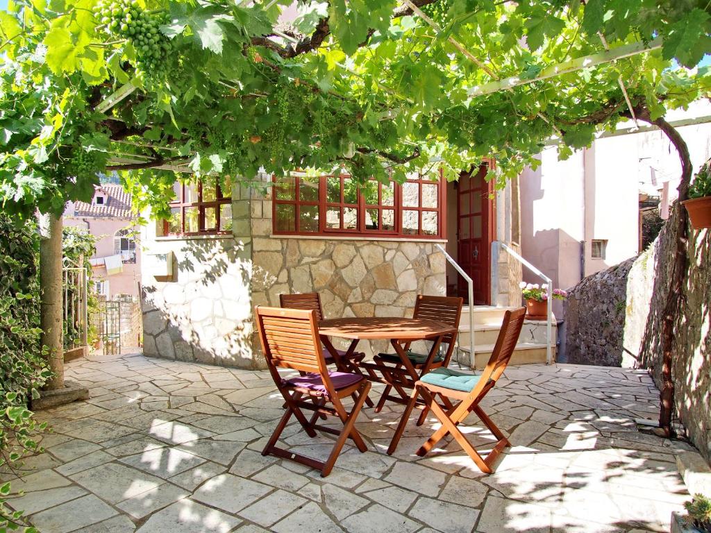 un patio con mesa y sillas bajo un árbol en Apartment Kameo with terrace, en Dubrovnik