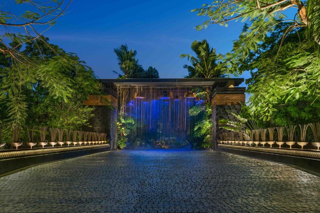 an entrance to a garden with a waterfall at night at The St. Regis Bali Resort in Nusa Dua