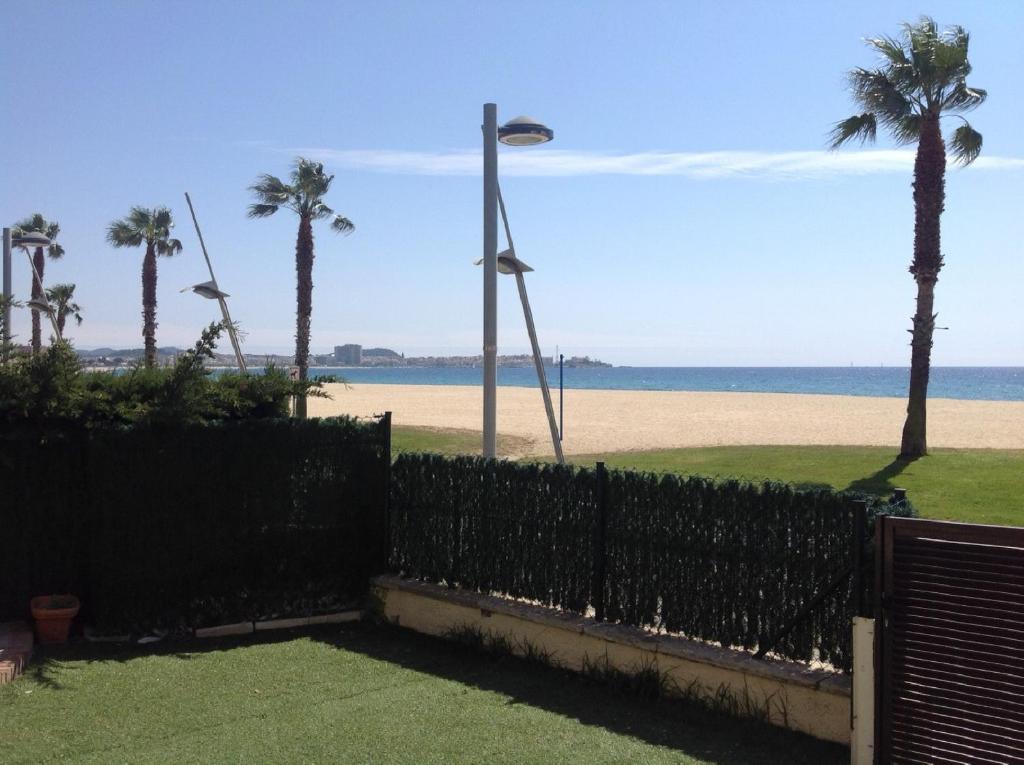 a fence in front of a beach with palm trees at Valentina Platja in Sant Antoni de Calonge