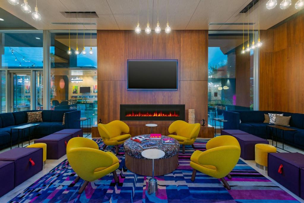 a lobby with yellow chairs and a fireplace at Aloft Orlando Downtown in Orlando