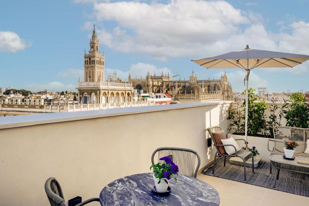 a balcony with a table and chairs and a view of the city at Querencia de Sevilla, Autograph Collection in Seville
