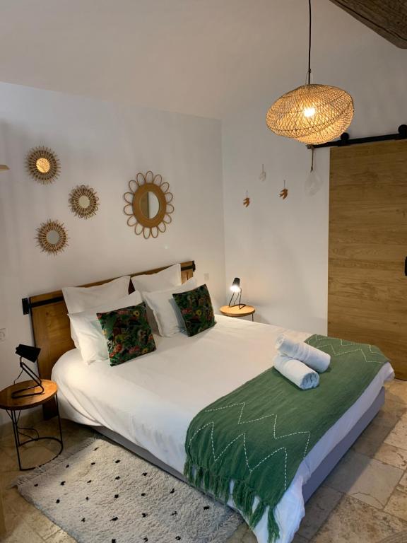 Un dormitorio con una gran cama blanca y una lámpara de araña. en Mazet LEAJO, en Eygalières