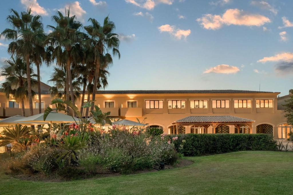 a building with palm trees in front of it at Hacienda Son Antem Golf Resort, Autograph Collection in Llucmajor
