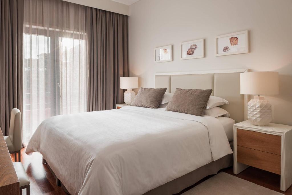 a white bedroom with a large bed and a window at Sheraton Cascais Resort - Hotel & Residences in Cascais