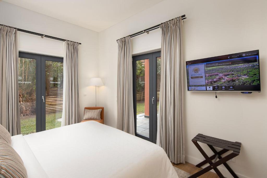 a bedroom with a bed and a flat screen tv at Sheraton Cascais Resort - Hotel & Residences in Cascais