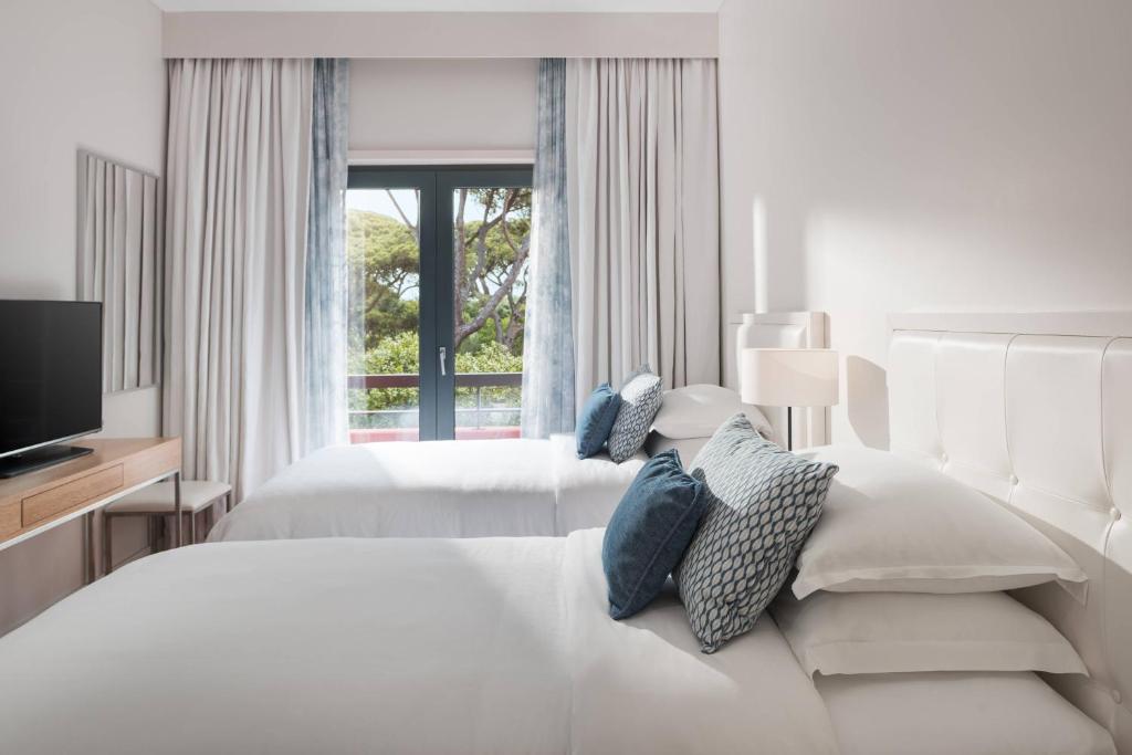a white bedroom with two beds and a window at Sheraton Cascais Resort - Hotel & Residences in Cascais