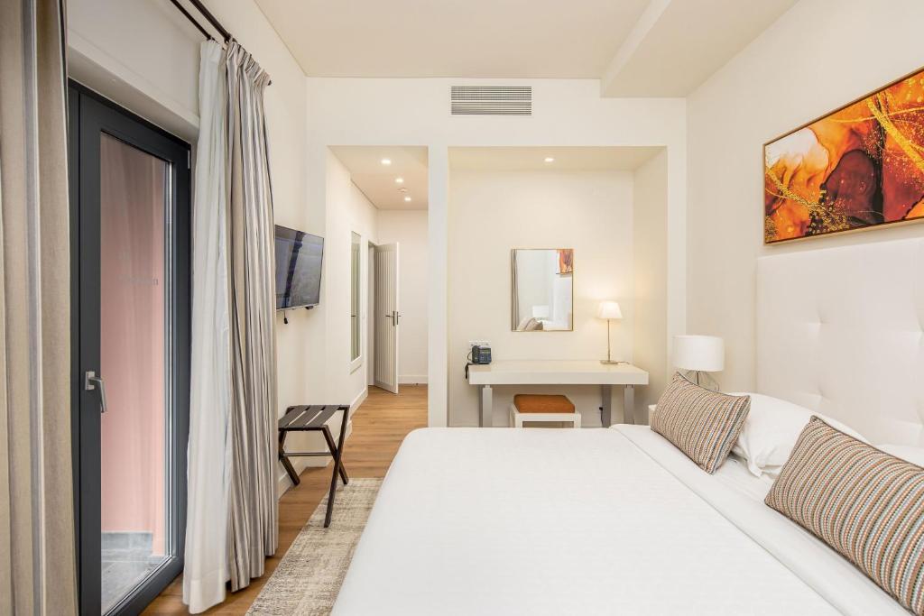 a white bedroom with a bed and a desk at Sheraton Cascais Resort - Hotel & Residences in Cascais