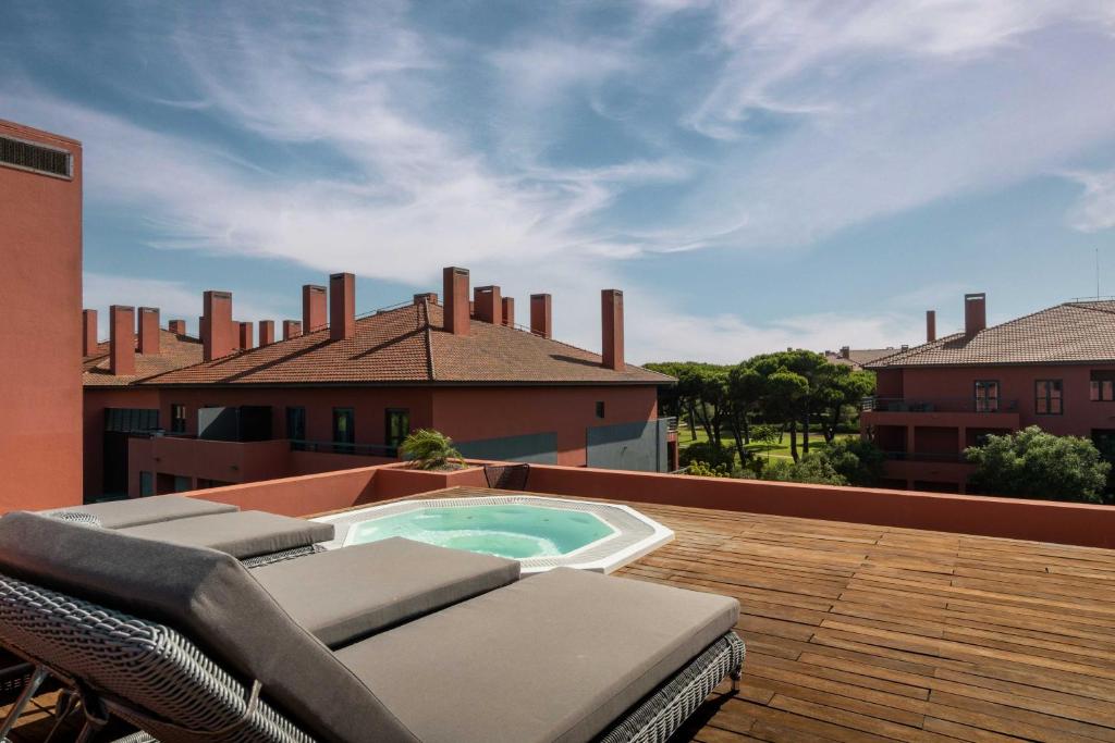a patio with chairs and a swimming pool on a roof at Sheraton Cascais Resort - Hotel & Residences in Cascais