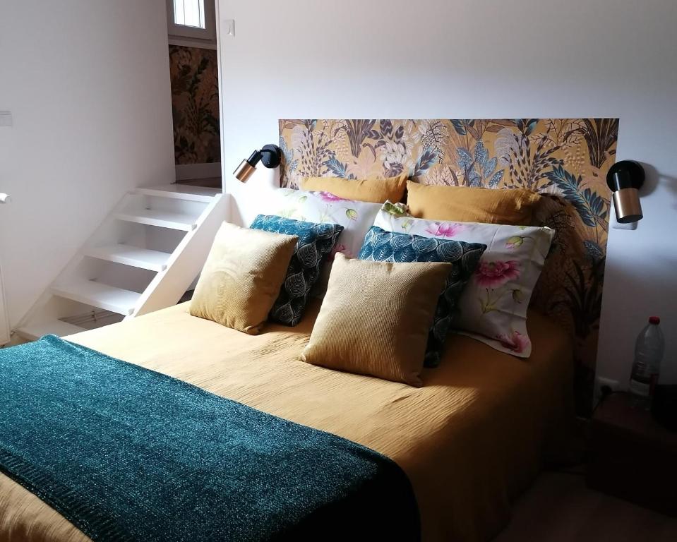 Una cama con un montón de almohadas encima en maison bois, en Ruaudin