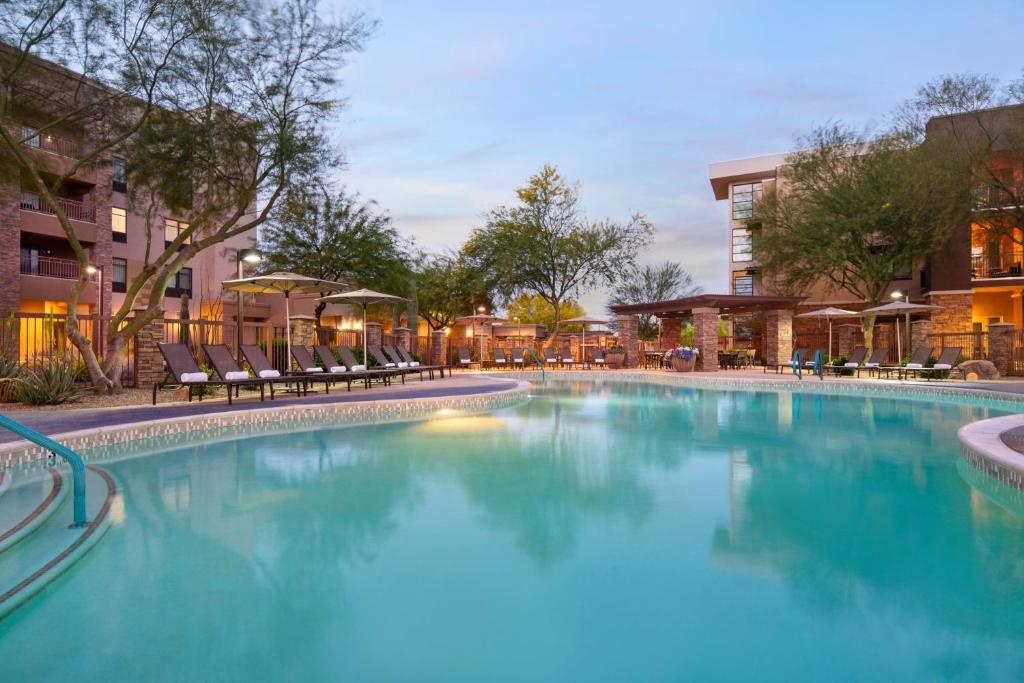 a large swimming pool with chairs and a building at Courtyard by Marriott Scottsdale Salt River in Scottsdale