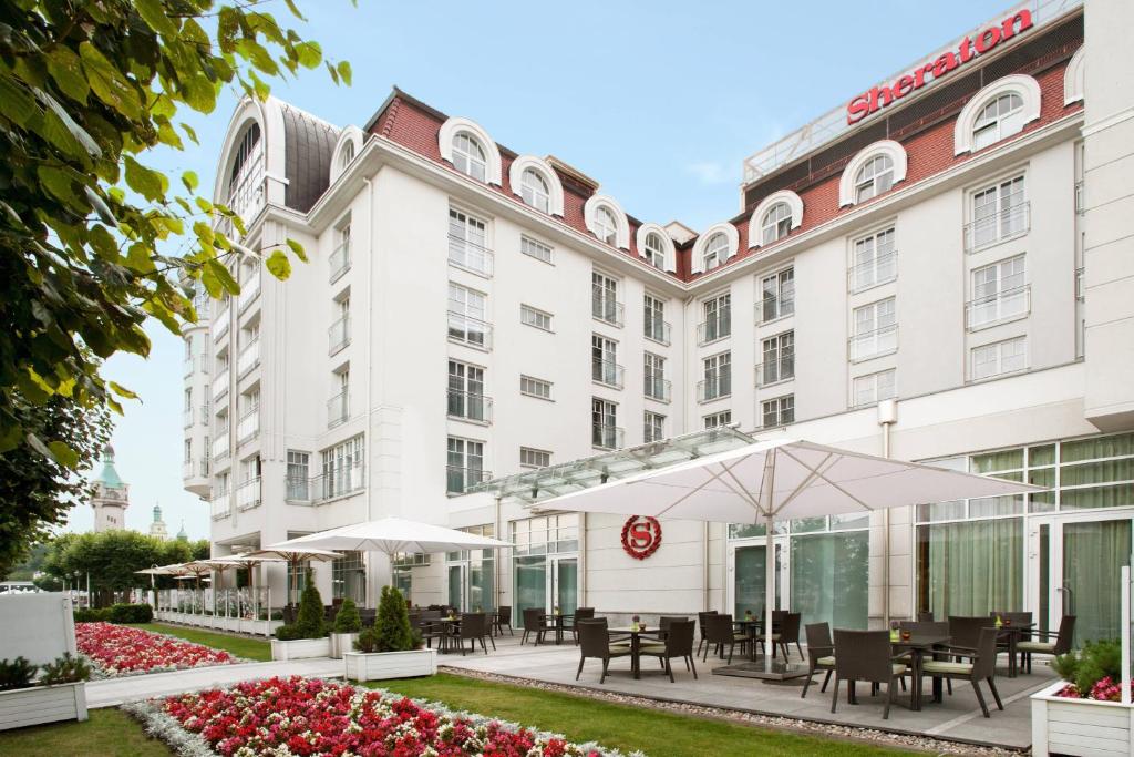 an exterior view of a hotel with tables and umbrellas at Sheraton Sopot Hotel in Sopot