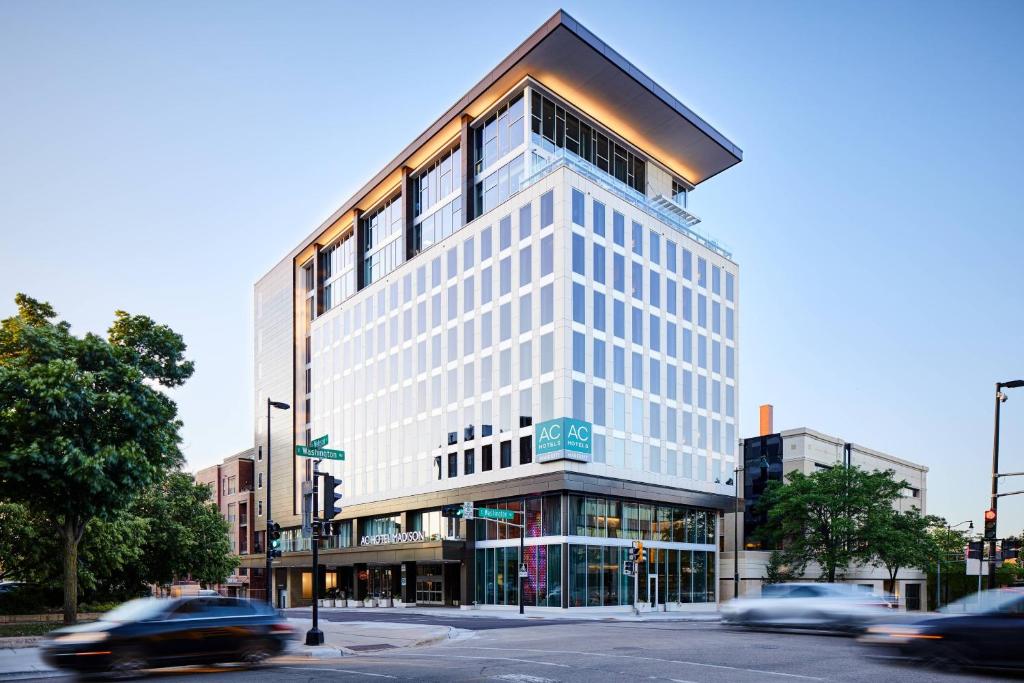 a tall white building on a city street with cars at AC Hotel by Marriott Madison Downtown in Madison