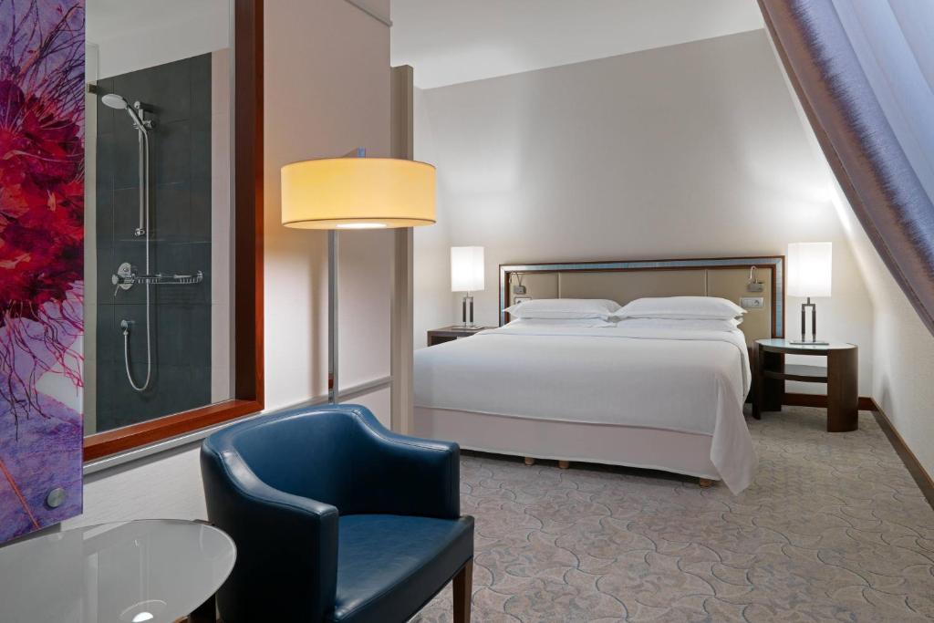 a bedroom with a bed and a chair and a shower at Sheraton Sopot Hotel in Sopot