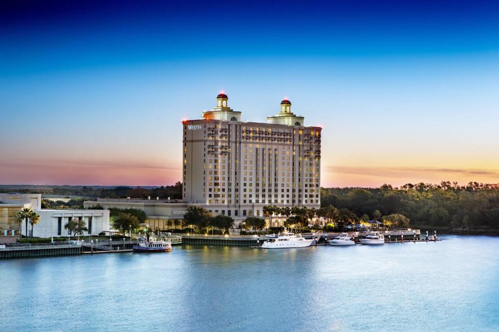 ein großes Gebäude neben einem Fluss mit Booten darin in der Unterkunft The Westin Savannah Harbor Golf Resort & Spa in Savannah