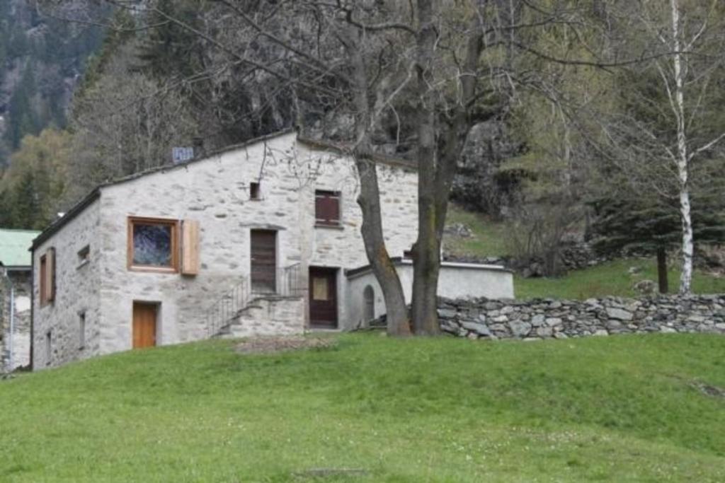 una casa de piedra sentada en la parte superior de un campo verde en Maiensäss La Scera Val Poschiavo, 