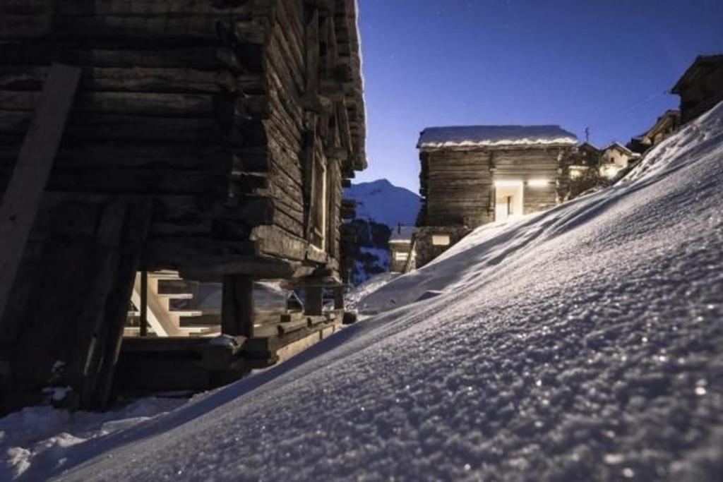 a snow covered slope next to a wooden building at Mayen à Etienne in Haudères