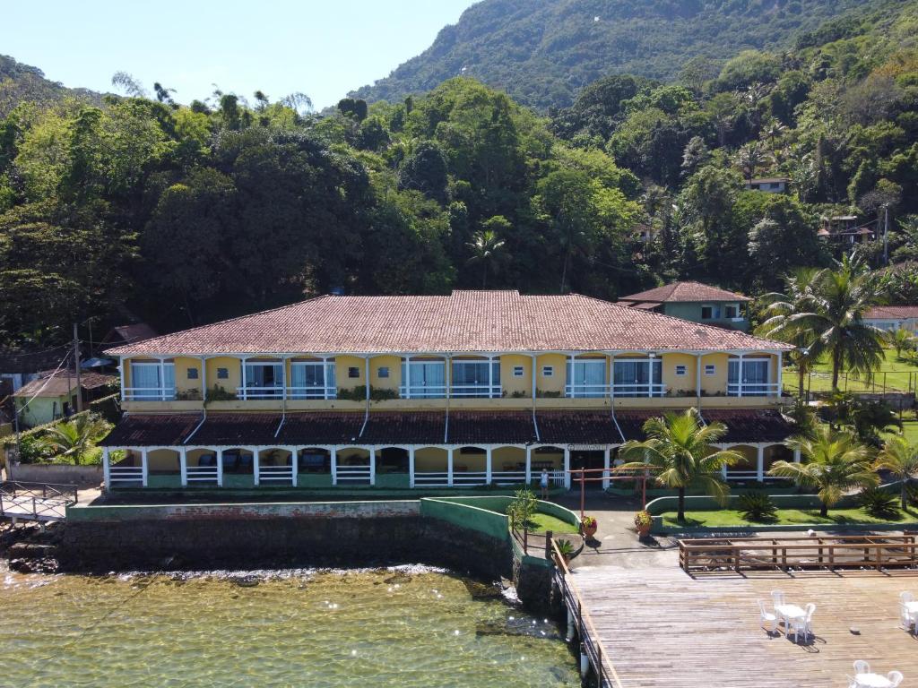 a house on the water with mountains in the background at Pousada do Preto in Praia do Bananal