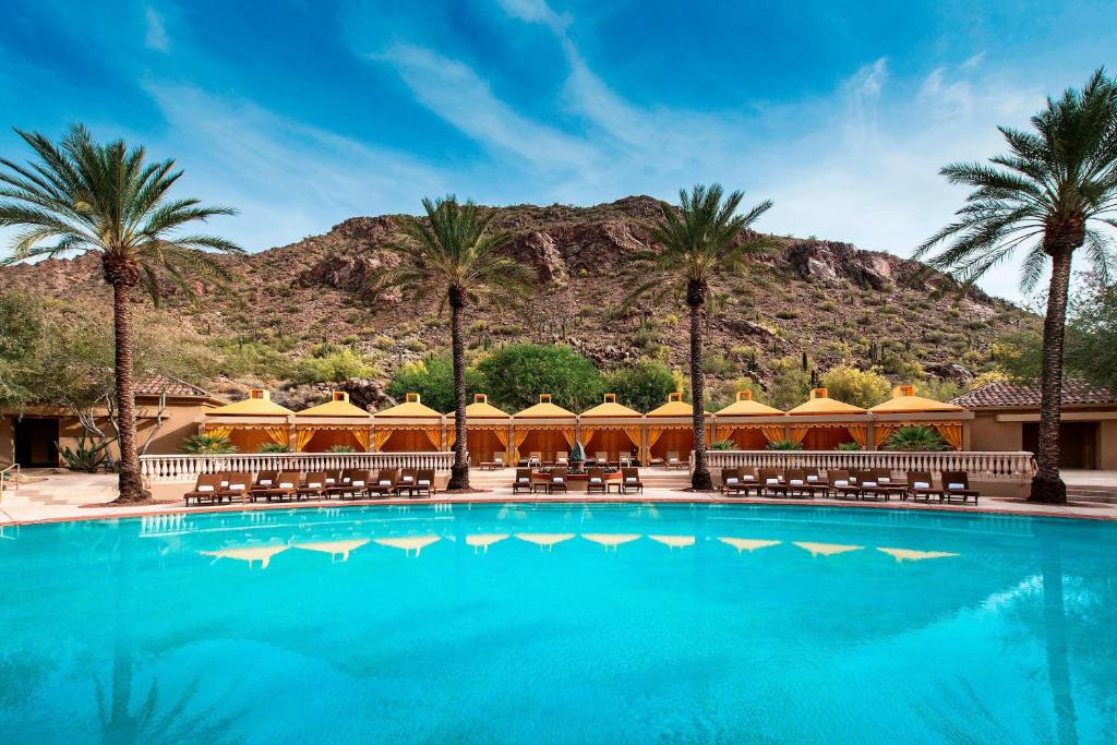une piscine avec des palmiers et des montagnes en arrière-plan dans l'établissement The Canyon Suites at The Phoenician, a Luxury Collection Resort, Scottsdale, à Scottsdale