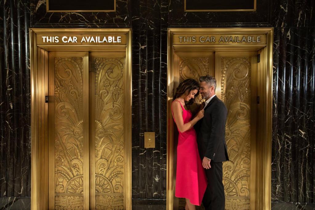 a man and a woman standing in front of two doors at JW Marriott Essex House New York in New York