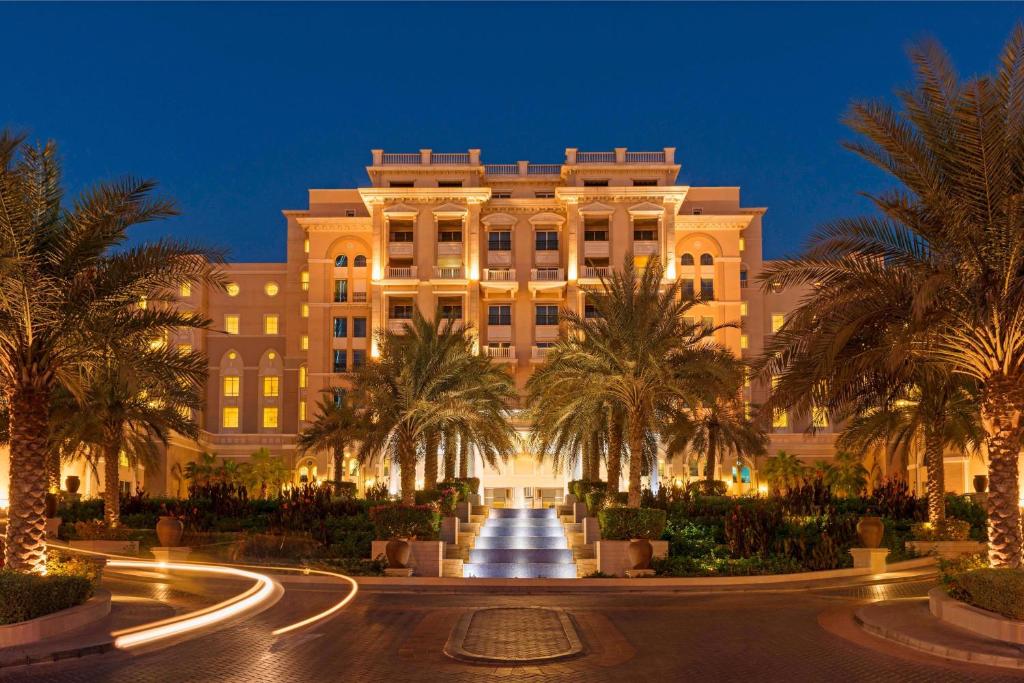 a large building with palm trees in front of it at The Westin Dubai Mina Seyahi Beach Resort and Spa in Dubai