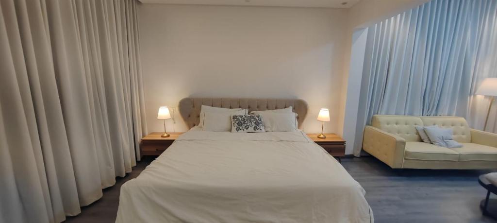 1 dormitorio con 1 cama blanca grande y 1 sofá en فيلا ضاحية الرمال, en Riad