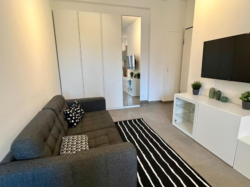 een woonkamer met een bank en een flatscreen-tv bij Cozy Apartment San Siro in Milaan