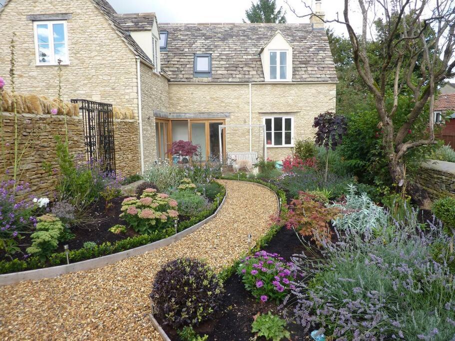 Sherston的住宿－Little Maunditts Cottage - quiet location in charming Cotswold village，鲜花屋前的花园