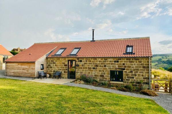 a brick house with a red roof and a yard at Green End Farm Cottages - The Cow Barn in Goathland
