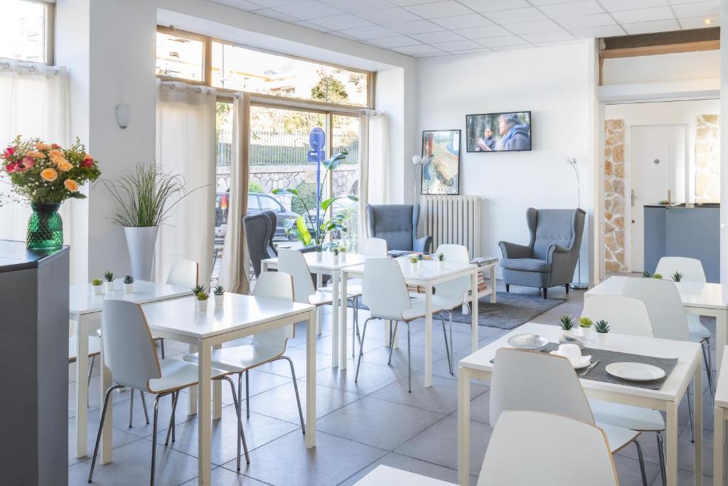 un ristorante con tavoli e sedie bianchi e finestre di Hotel De Belgique à Menton a Mentone