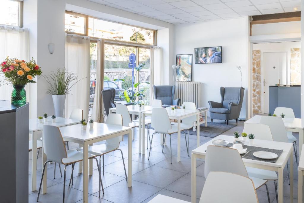 a restaurant with white tables and chairs and windows at Hotel De Belgique à Menton in Menton