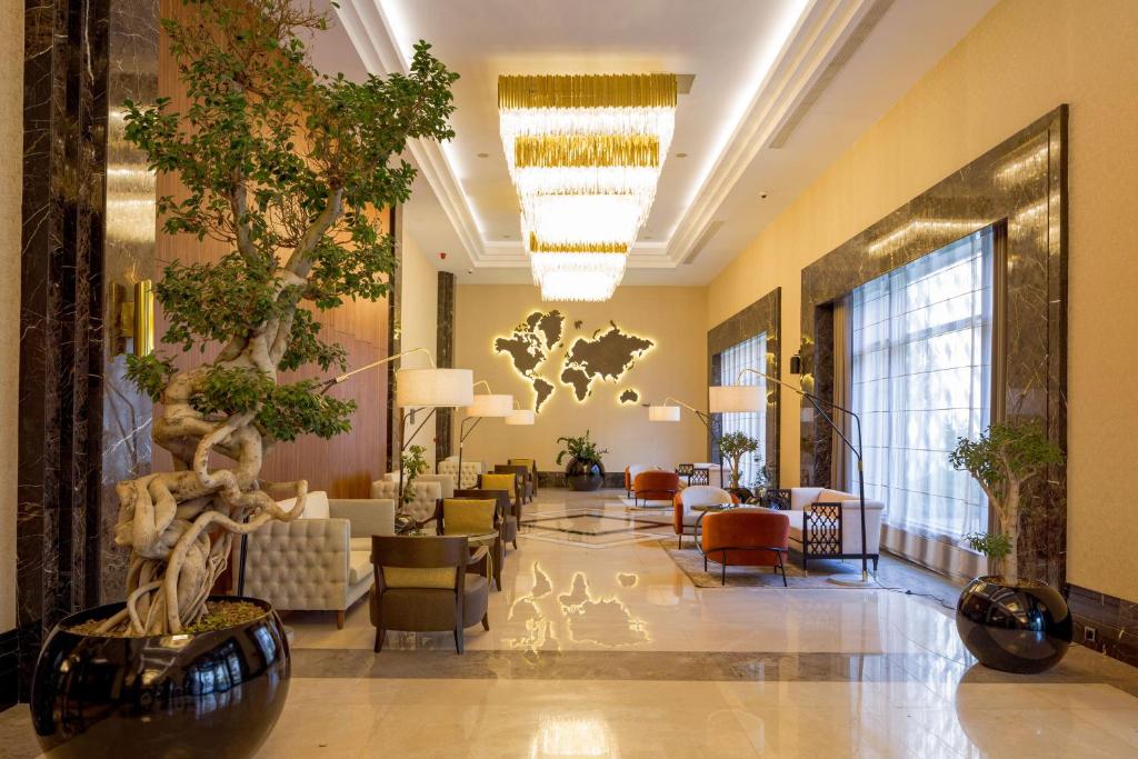 Sheraton Bishkek في بيشكيك: لوبي فندق فيه كنب وشجرة